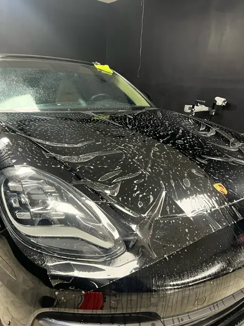 Paint protection film being fitted to the hood of a Porsche