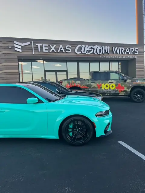 Tiffany blue Charger and a camo wrapped radio station truck outside the Texas Custom Wraps shop